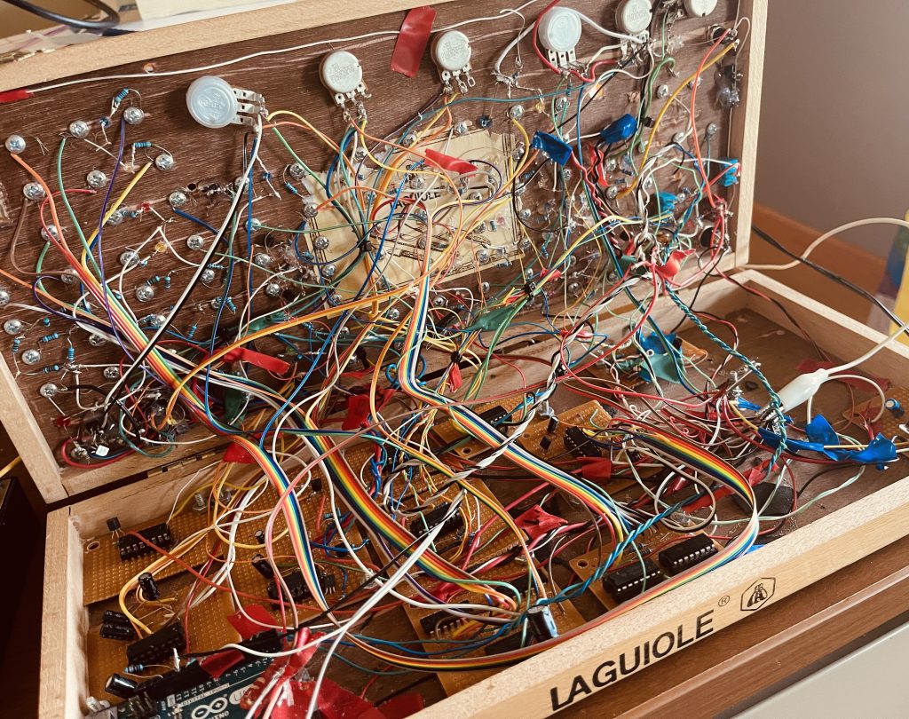 the inside of a small orange synthesizer absolutely packed with wires, wires everywhere. Very messy